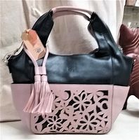Full view of ESPE handbag showing black upper section, pink bottom portion with floral cutout design, handles, and tassel detail.