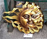 Front view of metal sun wall art showing full piece with curled sun rays and a smiling face expression