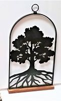 Metal Tree of Life cutout on wooden base, arched frame with hanging ring at top.