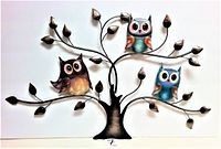 Front view of metal wall art showing three colorful owls on a black metal tree with decorative bronze leaves, against a white background.