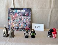 Book "Great Shakes" with salt and pepper shakers including Empire State Building, Chrysler Building, railroad lanterns, and hugging friends.