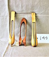Three wooden musical spoons displayed upright on a neutral fabric background, showing front and side profiles.
