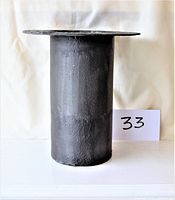 Front side view of black cast metal top hat shaped planter with cylindrical body and wide brim
