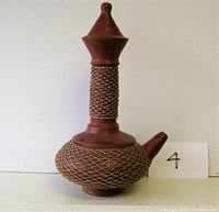 Front side view of the ceramic carafe showing conical lid and wire mesh wrapped on neck and body.