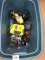 Blue plastic bin containing two yellow Ryobi ONE+ battery chargers and multiple batteries.