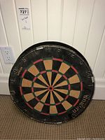 Full view of a round dart board labeled Unicorn with standard scoring and segments, showing general wear.