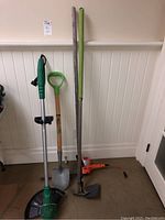 Full view of all garden tools including electric trimmer, weed wacker, shovel, and hoe.