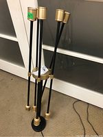 Full view of the black and gold ceiling light fixture with six upright rods ending in bulb sockets.