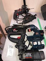 Multiple power tools including Skil jigsaw, Ryobi cordless drill, and several corded drills by Black & Decker and Sears Craftsman on a white table surface.