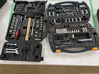 Overview of both tool sets open in plastic cases, showing sockets, wrenches, ratchets, and a mallet.