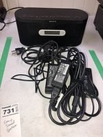 Multiple adapter cords with different plugs and black Sony sound system shown behind.