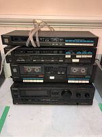 Four Technics stereo components stacked: FM/AM tuner, amplifier, cassette player with dual decks, and receiver with control knobs.