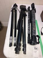 Three tripods placed on a white table, different designs and finishes visible.