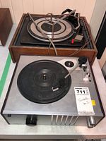 Two vintage turntables, Garrard and Crosley, placed on a surface; Garrard atop wooden base and Crosley below with visible cables and tonearms.