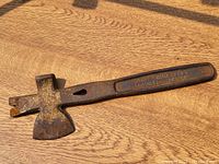 Full view of the antique roofing hammer showing the axe blade and text on the handle.