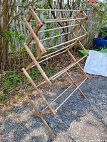 Front-left view of wooden drying rack set up outdoors showing three tiers and frame