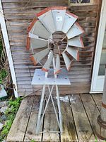 Front view of full windmill on tripod stand against wooden backdrop