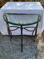 Front view of the D-shaped glass and metal end table showing the glass top and curved metal frame.