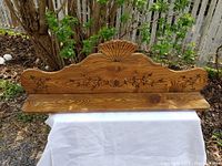 Full view of the oak hanging shelf showing fan motif and floral carvings on backboard with visible wood grain.