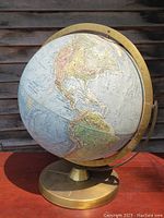 Full view of the old globe showing North and South America, brass base, and brass meridian ring.
