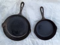 Pair of two cast iron frying pans viewed from above, showing the larger Smart pan and the smaller unmarked pan.