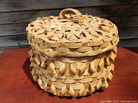 Front view of round vintage lidded basket showing the detailed split weave with loop designs and handle on the lid.