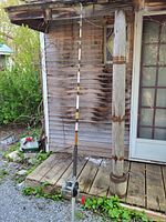 Full view of the entire fishing rod with reel attached, standing against a wooden porch.
