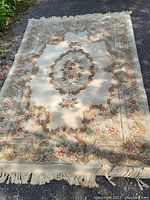 Full view of the ivory-colored Aubusson style rug showing floral and ornamental pattern and fringe edges.