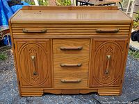 Full frontal view of the 1950s oak buffet with both cabinet doors and drawers visible, showing ribbed Deco-style detailing and brass handles.