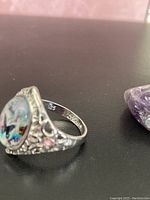 Ring shown at angle highlighting the detailed filigree and butterfly design under clear cabochon.
