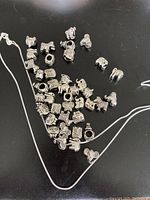 Photo showing 18 inch silver chain with many different animal-shaped and character silver charms laid out on a flat surface.