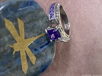 Close-up view of the amethyst ring showcasing the central square stone and part of the band with inlaid smaller stones.