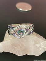 Front view of the sterling silver ring with visible topaz center stone and pink heart-shaped side gems with white gem swirls on the band.