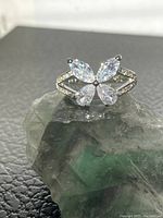 Front view of the 925 silver butterfly ring with clear cubic zirconia stones, placed on a greenish stone for display.
