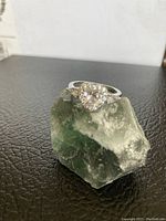Front angled view of the 925 sterling silver ring with heart-shaped cubic zirconia center on a green stone display.