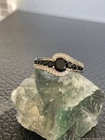 Front angle view of the CZ ring showing black and clear stones on a silver-toned band.