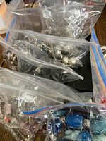 Photo showing multiple plastic zip-lock bags containing assorted necklaces with varied styles, colors, and bead types