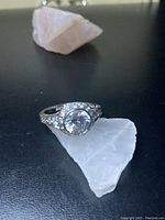 Front view of the sterling silver ring with large round cubic zirconia center stone placed on a white crystal.