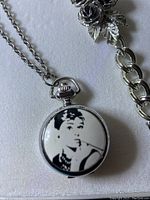 Photo showing pocket watch with Audrey Hepburn image and attached chain.