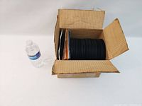 Box containing approximately 100 assorted 45 RPM vinyl records stacked vertically with some record sleeves visible.