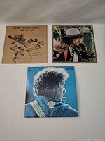 Top view of three Bob Dylan vinyl records showing the front covers of 'Slow Train Coming,' 'Desire,' and 'Greatest Hits Vol. II'.