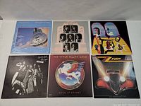 Six vinyl LP records laid on flat surface showing front album covers including Dire Straits, Alice Cooper, ZZ Top, Steve Miller Band, and others
