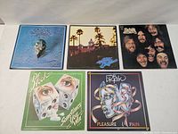 Front covers of 5 vinyl LP records: 3 Eagles albums including one with skull artwork, and 2 Dr. Hook albums with illustrated faces and dice.