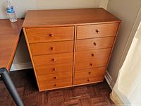 Full view of the wooden dresser showing 12 drawers with wooden knob handles and medium brown finish.