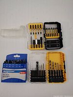 Three drill and driver bit sets showing bits and cases open, with various bits and adapters arranged inside.