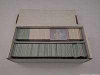 Open box showing hundreds of football cards inside, many in used condition with one card's front visible.