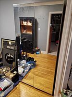 Front view of the cabinet showing two mirrored sliding doors, reflecting the room and various objects.