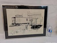 Framed signed John Mantha locomotive pen and ink print with numbering visible next to water bottle for scale.