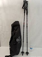 Full set showing the snowshoes, poles, and carrying case together, along with a water bottle for scale.