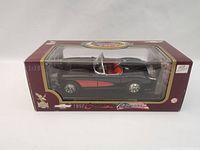 View of the boxed 1957 Chevrolet Corvette model from the side showing black-red color scheme and interior.